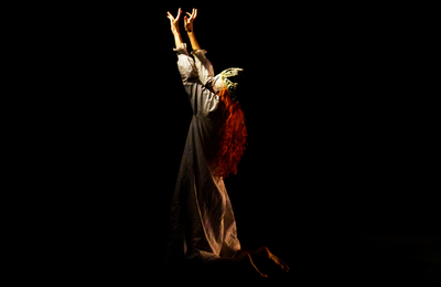 Photo du spectacle "Le bon fruit mûr" de Jeanne Lepers, avec le personnage féminin portant une couronne de reine, implorant à genoux.