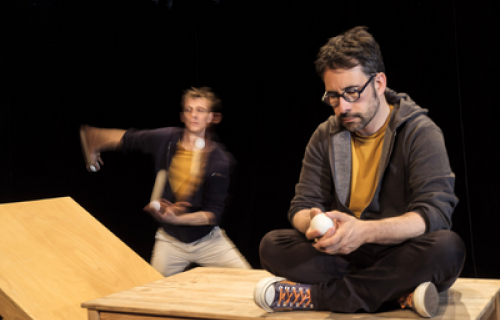 Photo du spectacle L'envers de nos décors de Clément Dazin et Thomas Scotto. Deux hommes sont sur des tables en pin avec des boules de jonglages.