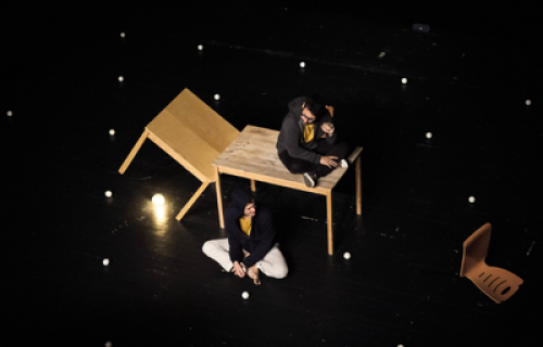 Photo du spectacle L'envers de nos décors de Clément Dazin et Thomas Scotto. Deux hommes sont sur des tables en pin avec des boules de jonglages.