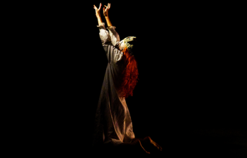 Photo du spectacle "Le bon fruit mûr" de Jeanne Lepers, avec le personnage féminin portant une couronne de reine, implorant à genoux.
